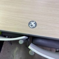 車椅子のシンボルマーク。一般的に見られる抽象的な車椅子マークではなく、漕ぎ手が上に振り上げられ、前傾姿勢でダイナミック。